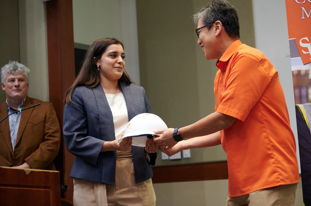 Isabel Rivera-Burkholder receives a hard hat from Professor Min Jae Suh.