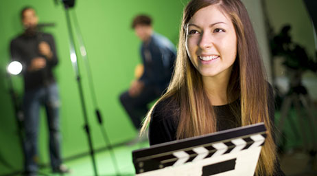 A person in front of other people using a green screen on a movie set.